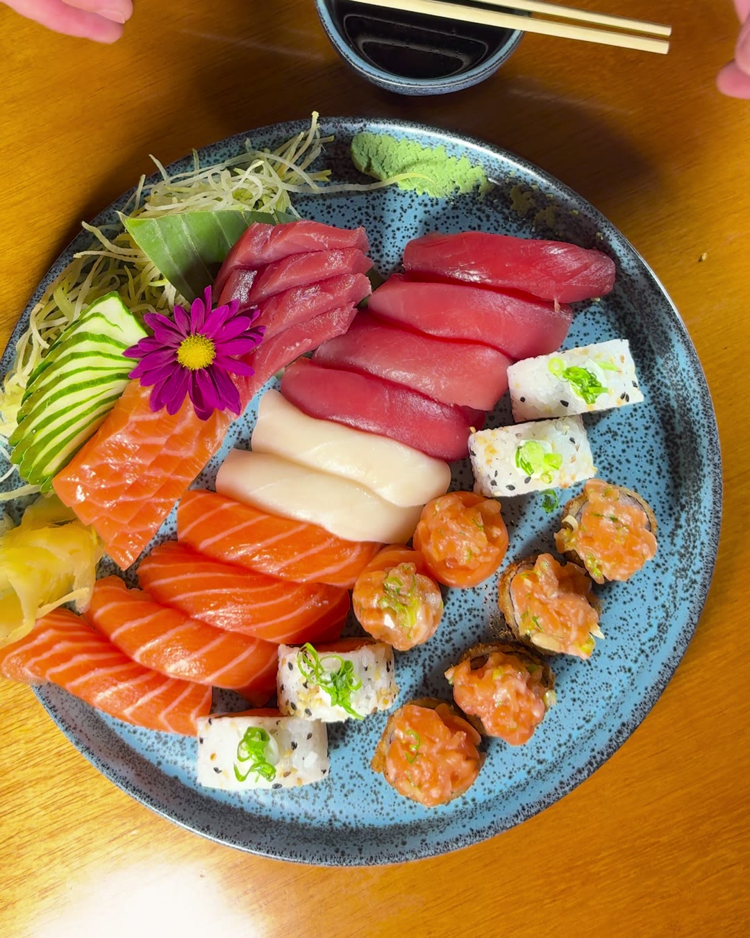 Combinado de sushi e sashimi em prato redondo, visto de cima