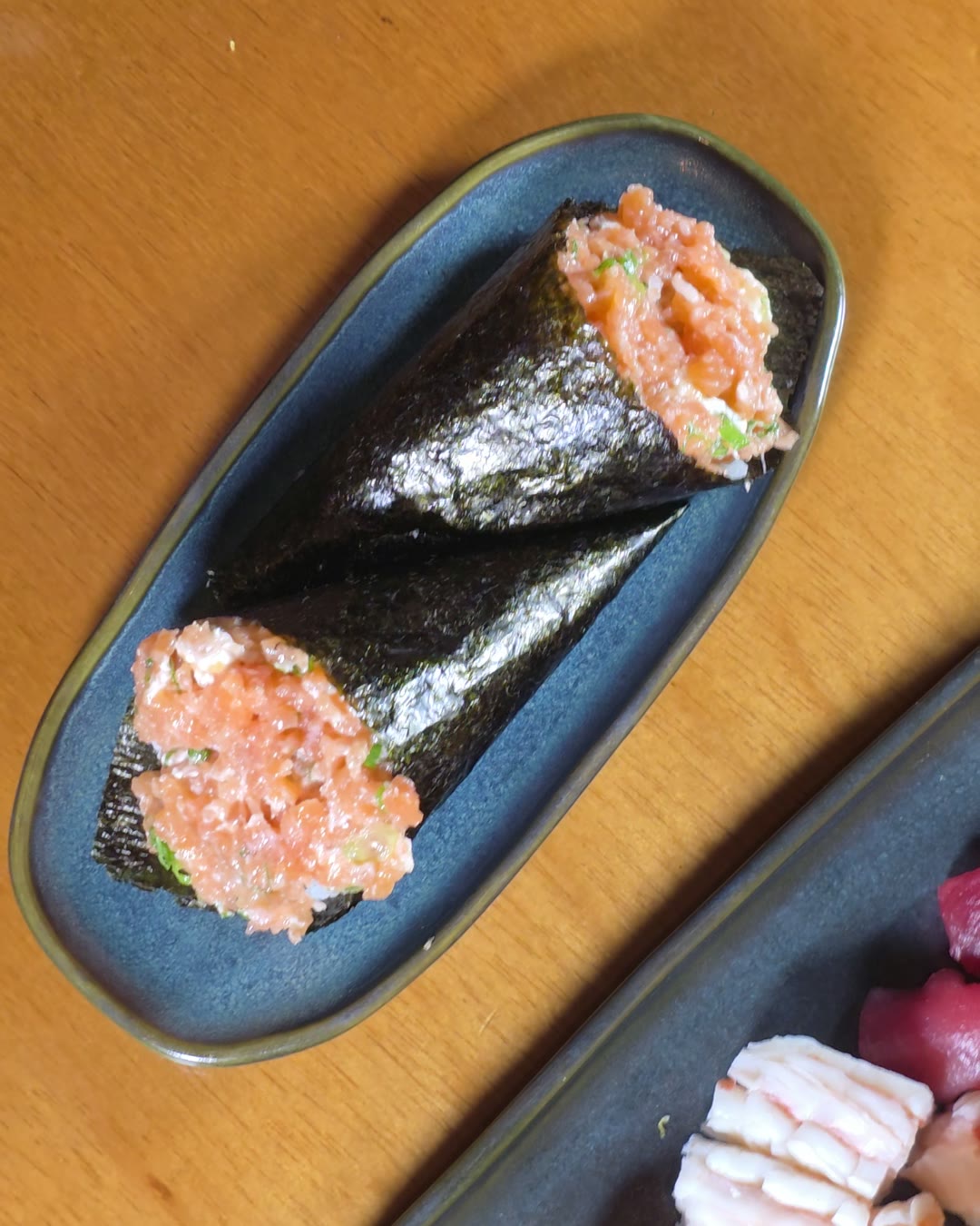 Temaki de salmão em prato azul, visto de cima